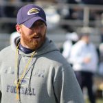 Trener sa riđom bradom u duksu sa kapuljačom nosi kačket